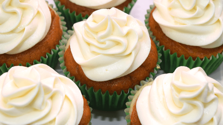 A close up view of multiple pumpkin cheesecake cupcakes all frosted with cream cheese buttercream frosting.