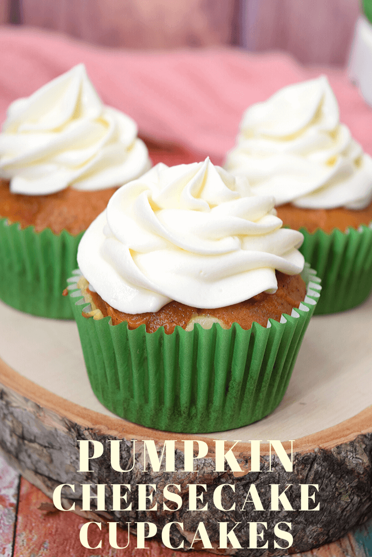A pumpkin cheesecake cupcake front and center on a wood slice. 