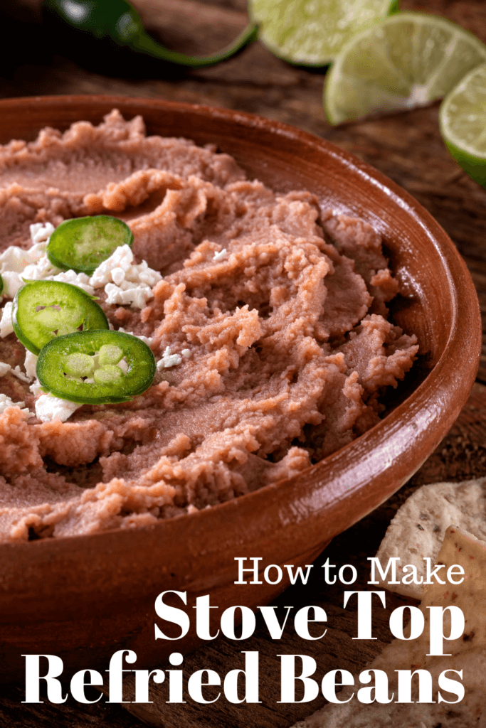 a brown bowl of refried beans topped with cheese and jalapenos