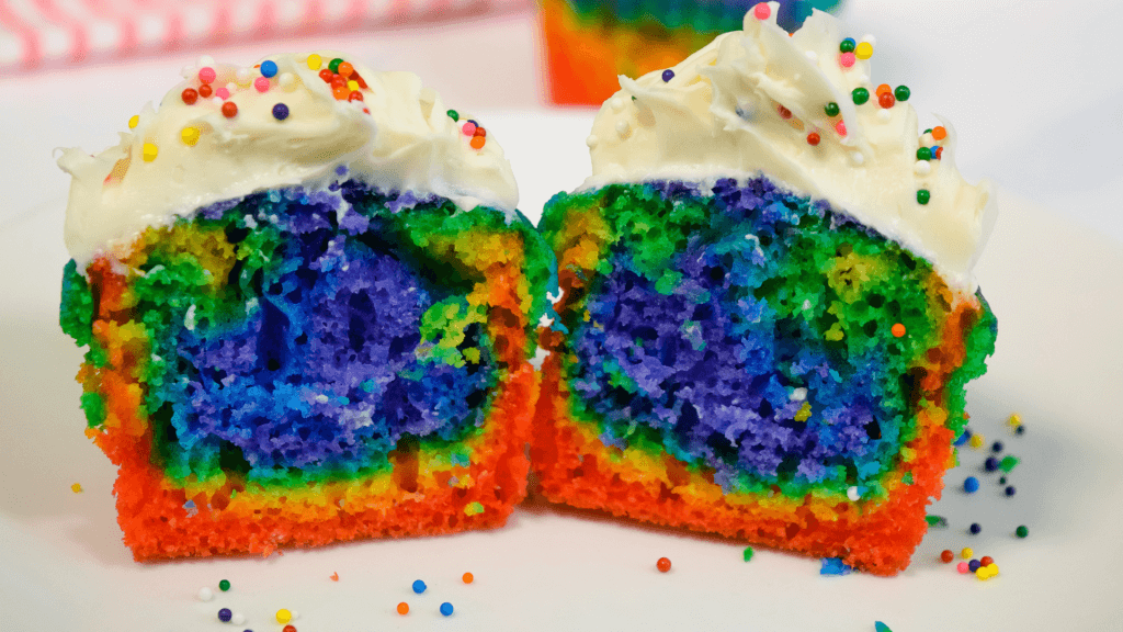 Rainbow Cupcake sliced in half to show layers of colors. 