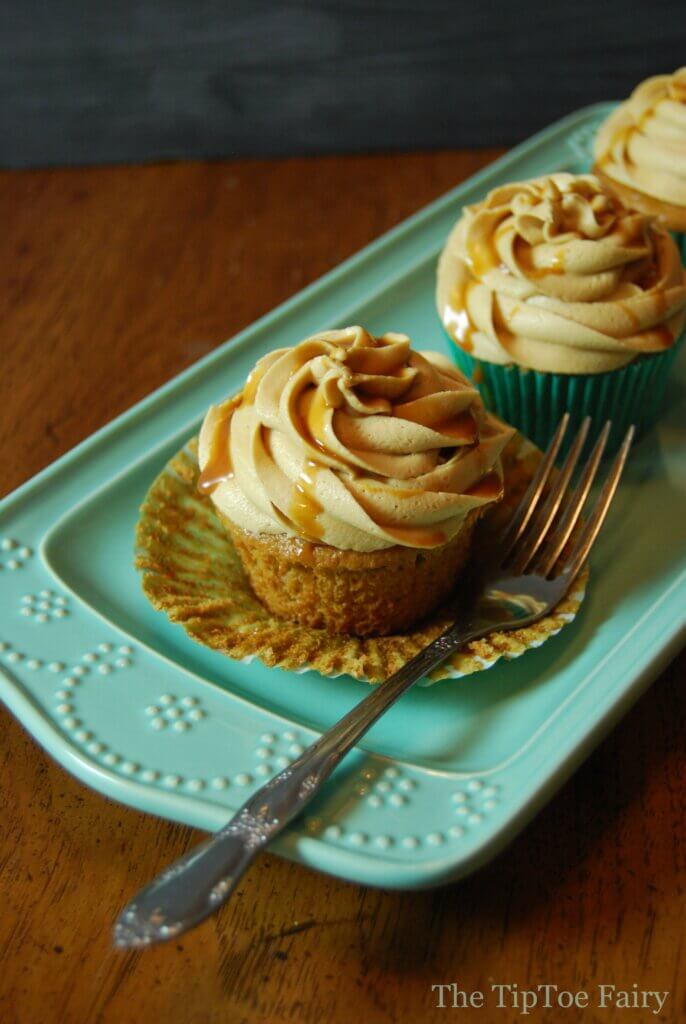 Dulce de Leche Cappuccino Cupcake unwrapped with a fork on a light blue platter. 
