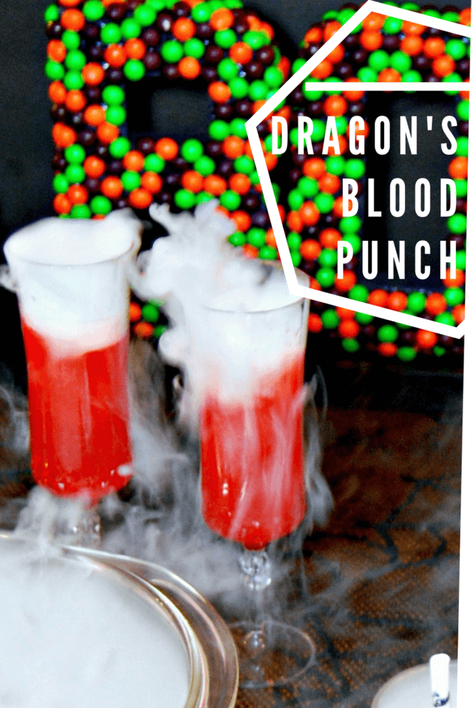 Title image for Dragon's Blood Punch with two champagne glasses of red dragon's blood punch with dry ice smoking off the top. 