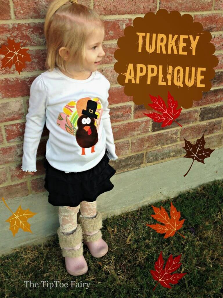 A little girl wearing a turkey shirt. 