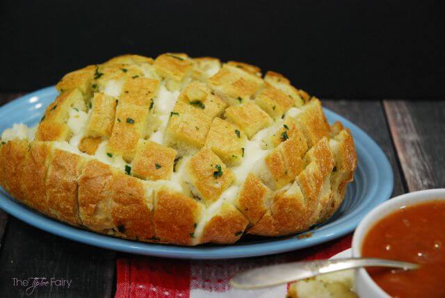 cheesy garlic pull apart bread on a blue platter and black background