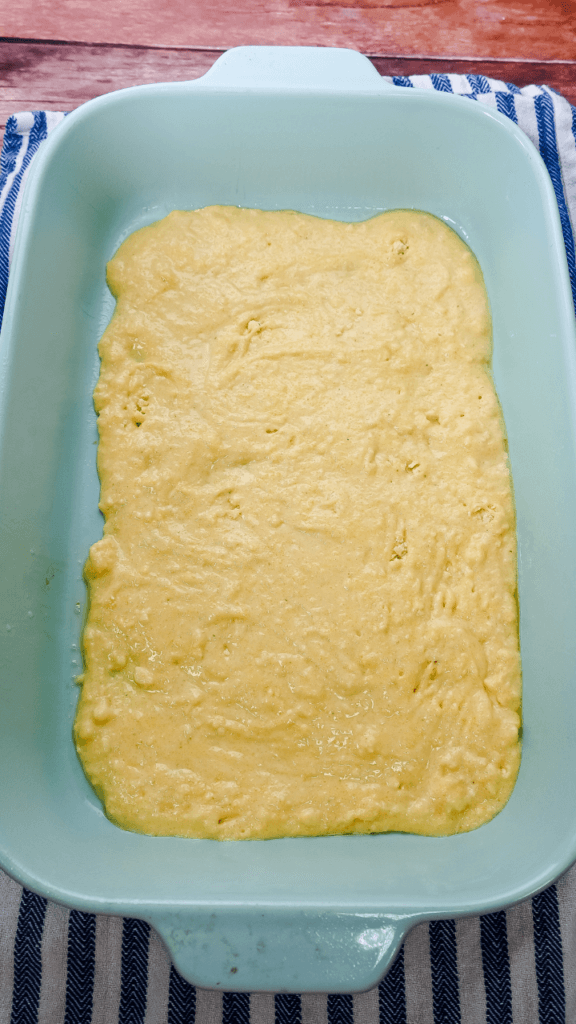 First layer of Cowboy Brisket Casserole is cornbread batter in a light blue casserole dish