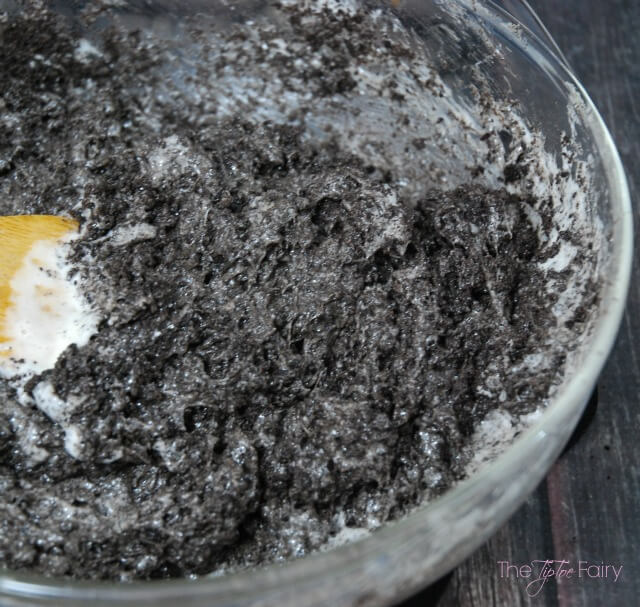 Mixing the melted marshmallows and OREO cookie crumbs in a glass bowl. 