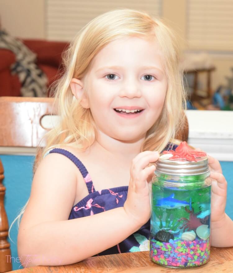 A little girl smiling and holding  a Light Up Mason Jar Aquarium! 