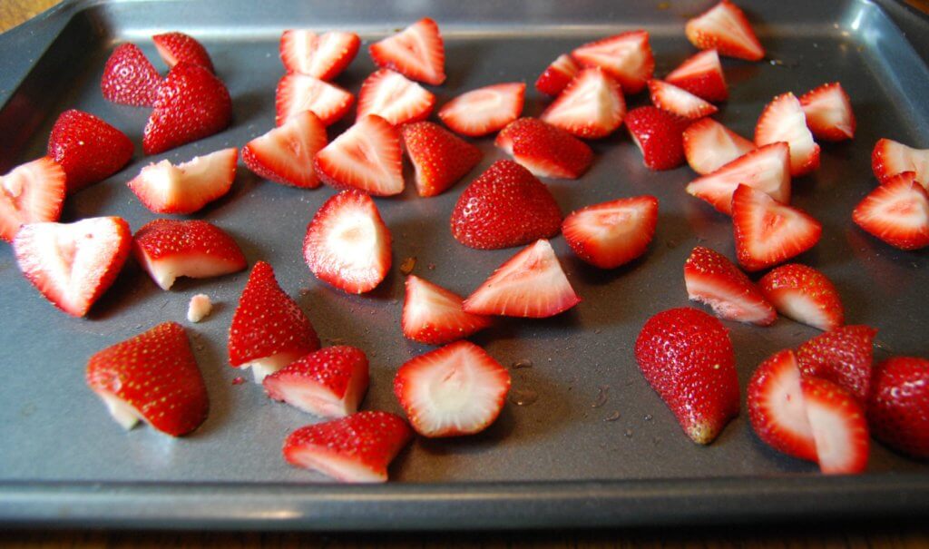 fresh strawberries sliced on a cookie sheet ready to be roasted
