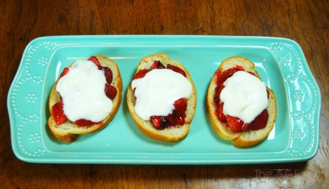 Three slices of roasted strawberry crostini on a blue platter