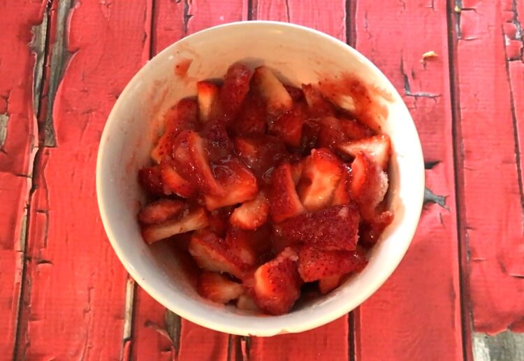A bowl of sliced strawberries mixed with strawberry preserves.