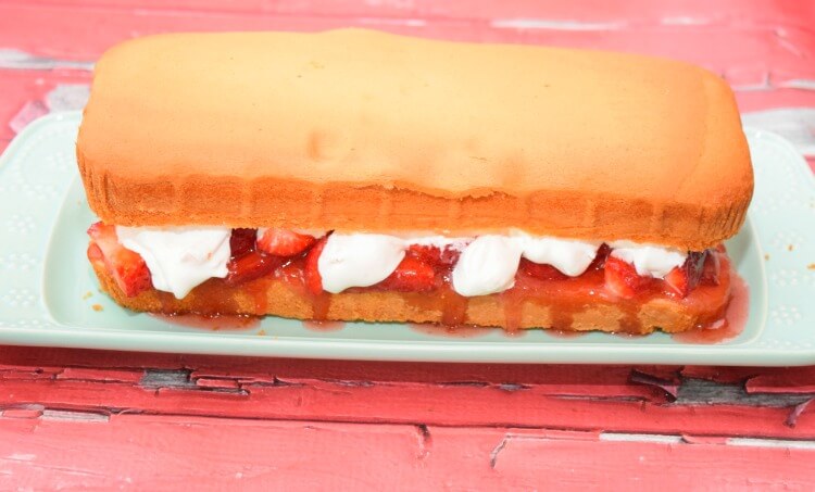 The pound cake sandwich layers with layers of strawberries and whipped cream between them.