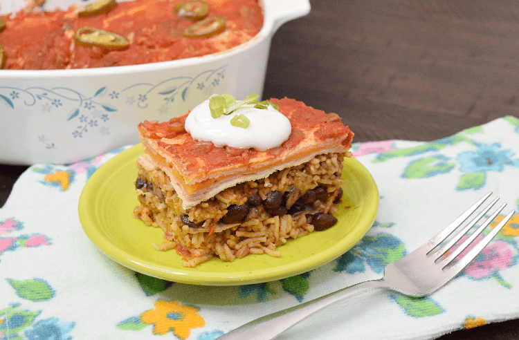 Finished Mexican Tortilla Lasagna topped with sour cream and onions. 