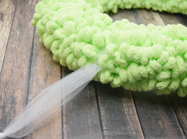 Add the ribbon or tulle to hang your wreath before adding the decorations to it. 