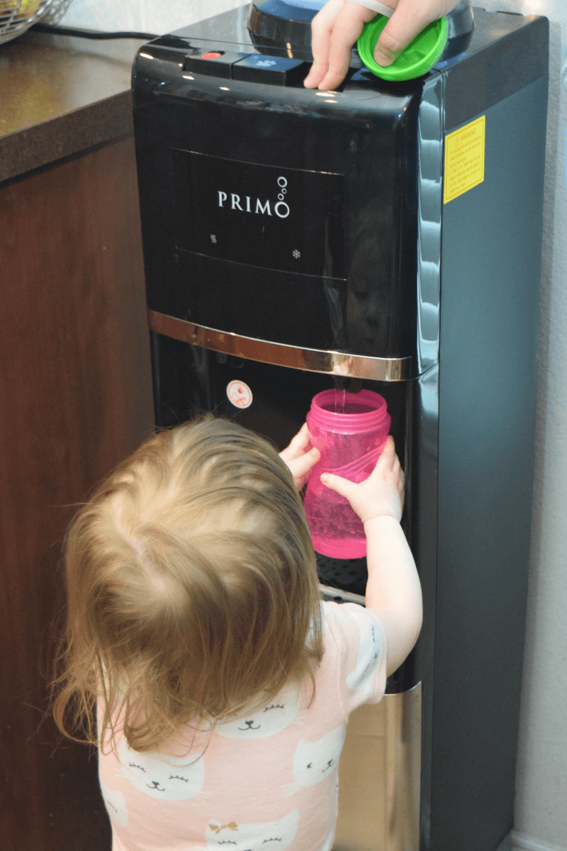 A toddler filling her sippy cup at the Primo Water Dispenser