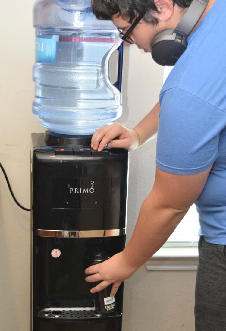 A teenager refilling his water bottle with the Primo Water Dispenser