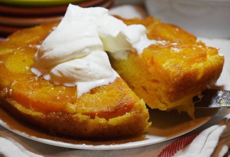 Lifting a slice up from the Apricot Upside Down Cake topped whipped cream. 