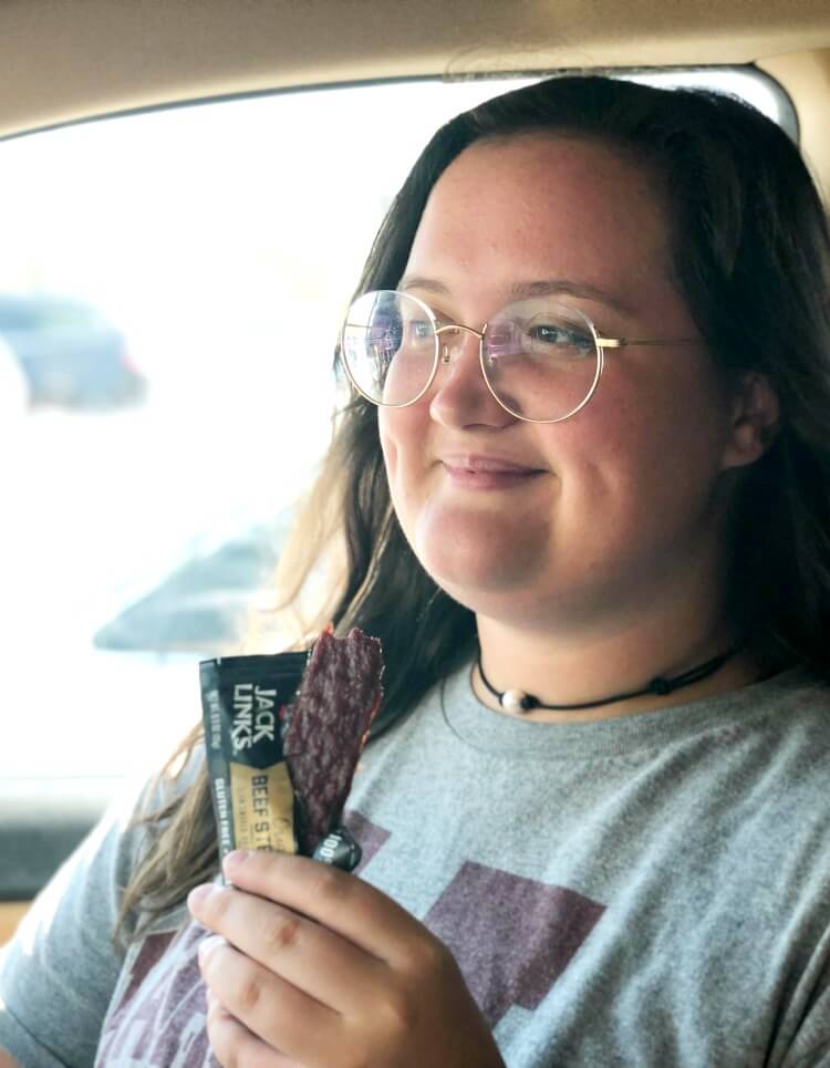 Teen girl eating a Jack Link's Bar in the car. 