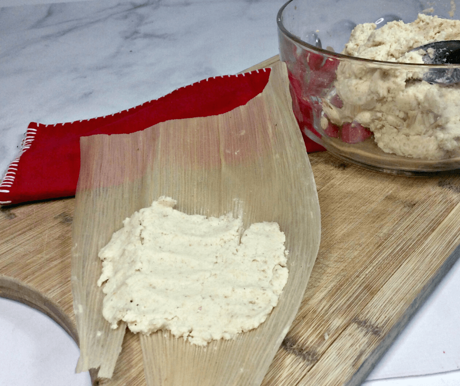 Spreading the masa harina in the corn husk for authentic pork tamales