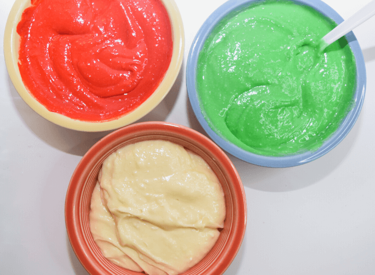 Divided bowls of cheesecake batter with two dyed red and green. 