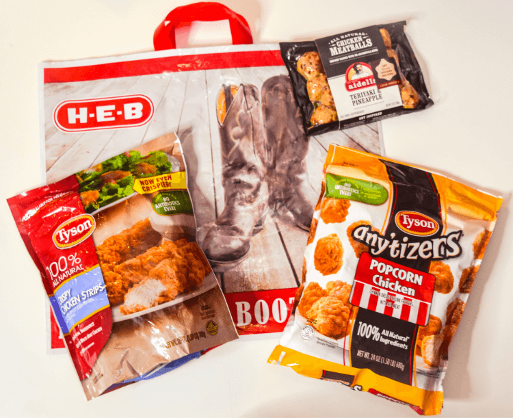 H-E-B reusable bag with packages of Tyson Crispy Chicken Strips, Aidells Meatballs, and Tyson Any'tizers Popcorn Chicken