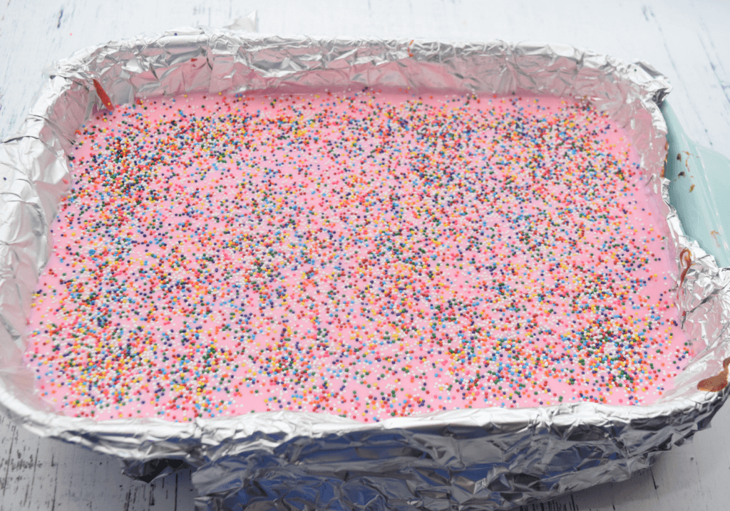 Rainbow sprinkles all over the pink ganache. 