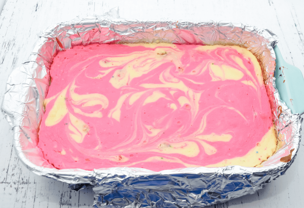 The baked cheesecake in the pan with swirls of pink and white cheesecake. 
