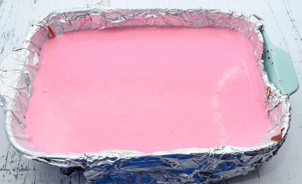 Pale pink ganache over the top of the entire cheesecake in the foiled pan. 