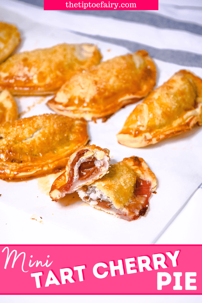 A close up image of finished mini tart cherry hand pies with one mini pie cut open. 