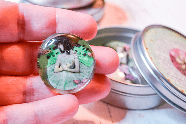 Close up image of a finished vintage DIY Magnet made from a cabachon, vintage image, and ceramic magnet in a hand. 