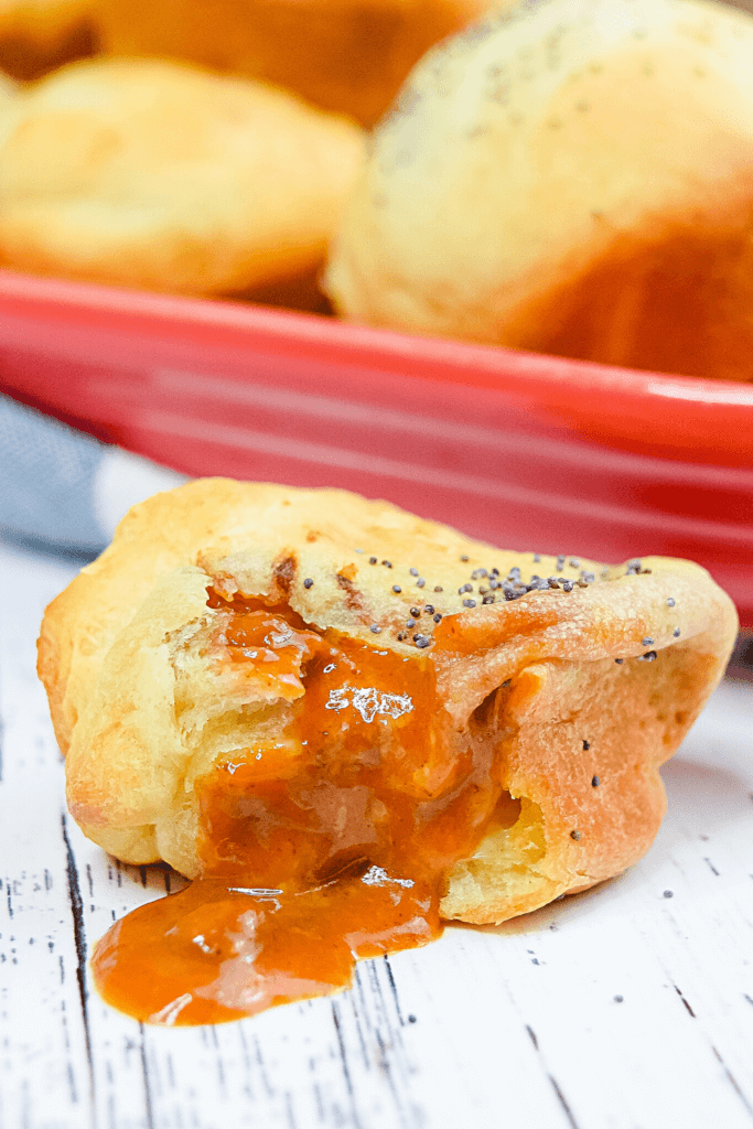 A close up shot of a single Chili Cheese Puff pulled open with chili oozing out.