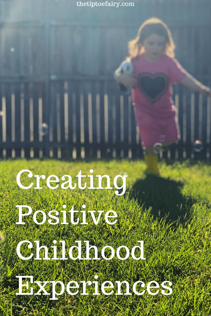 little girl in pink shirt running through the yard with bubbles. Creating Positive Childhood Experiences