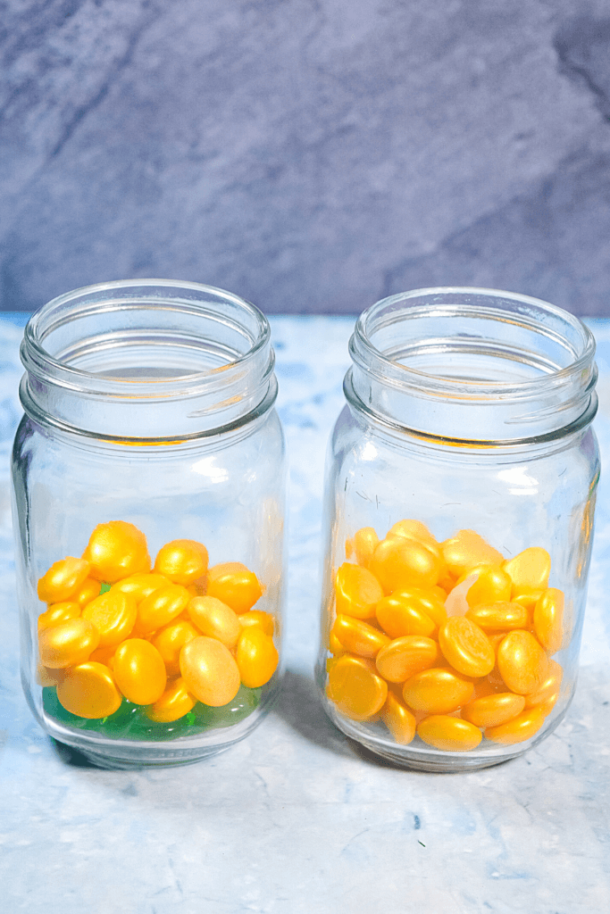 Mason jars with hidden tea lights under golden pebbles. 