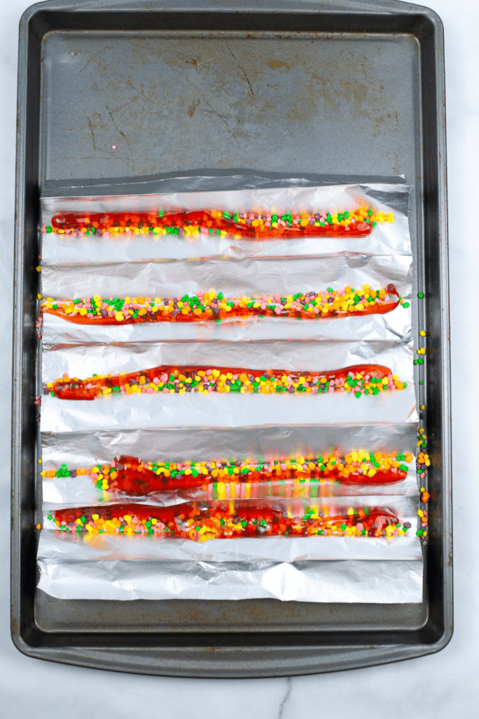 Cookie sheet with foil troughs filled with Nerds Candy and melted gummy bears. 