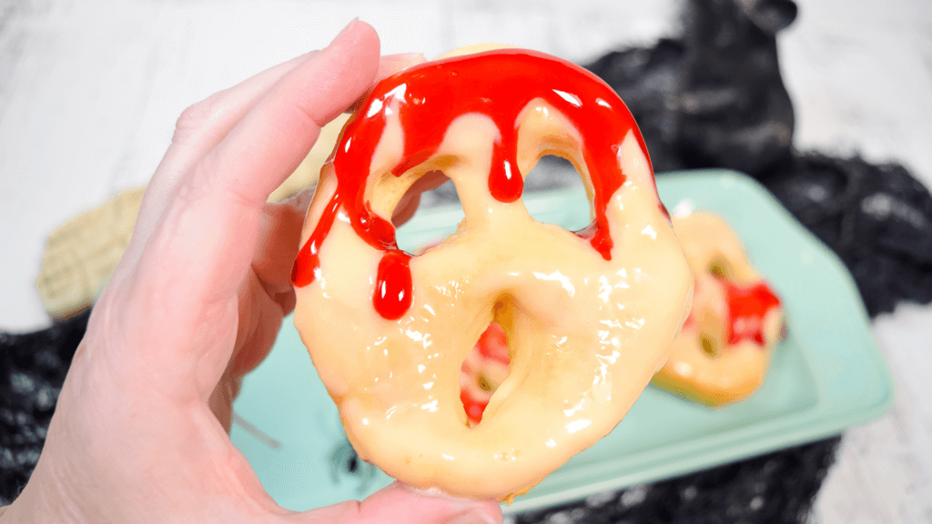 Finished image of a hand holding up a glazed and bloody screaming donut made in the air fryer