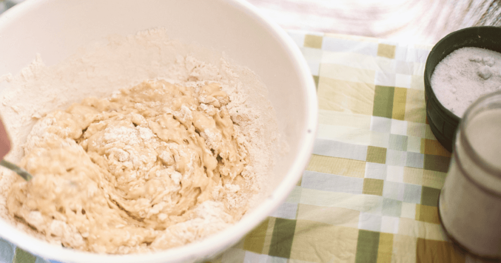 A white bowl full of pancake mix on a green checkered backdrop.