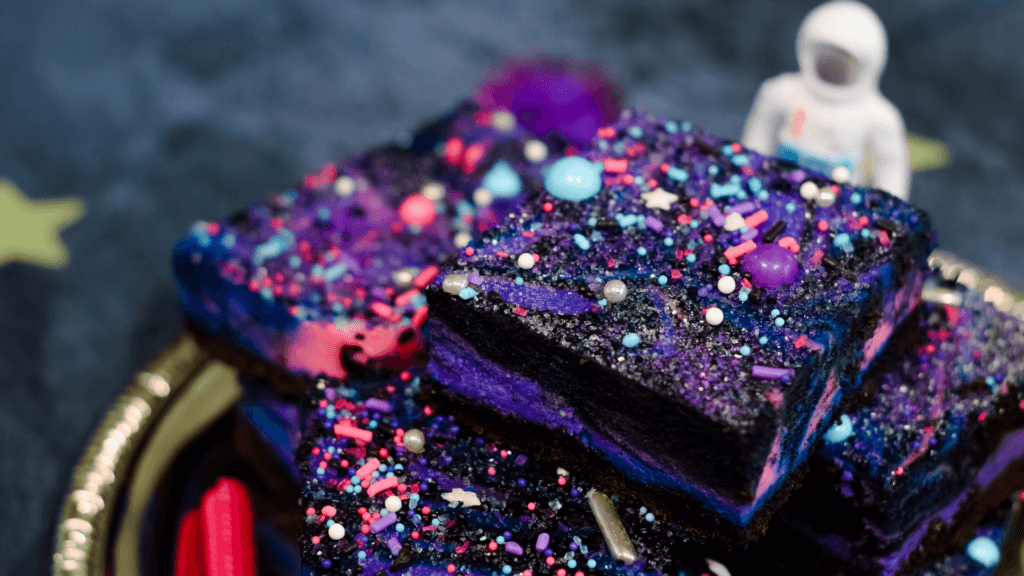 Galaxy Cheesecake Bars stacked on a silver plate on a dark background