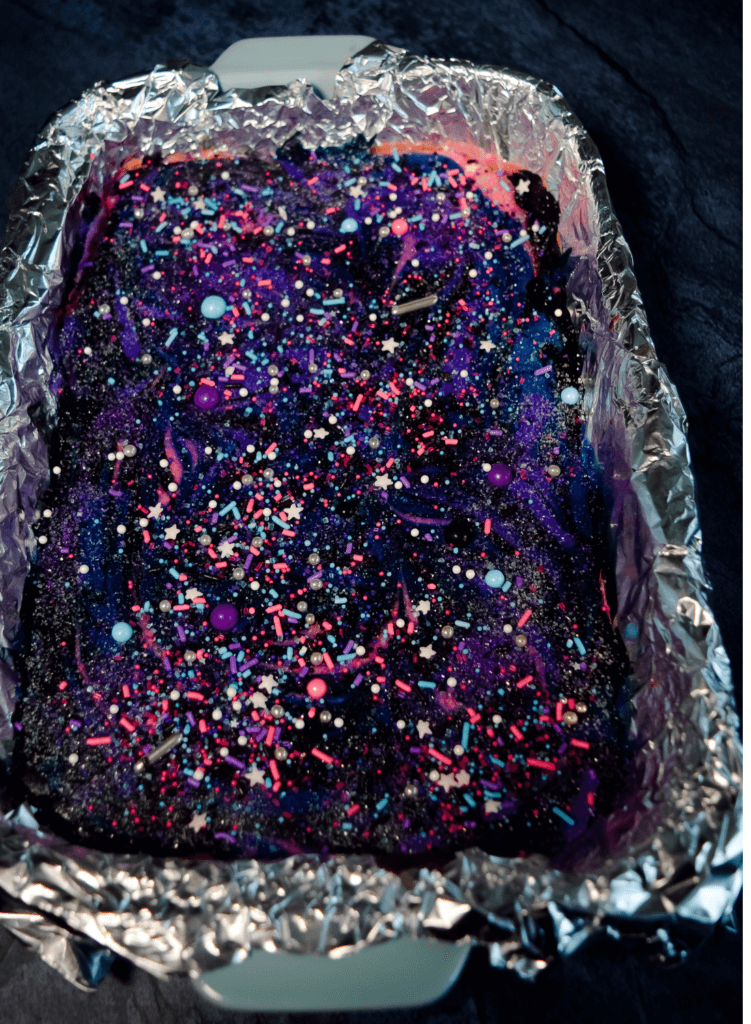 Galaxy Cheesecake covered in sanding sugar and galaxy sprinkles.