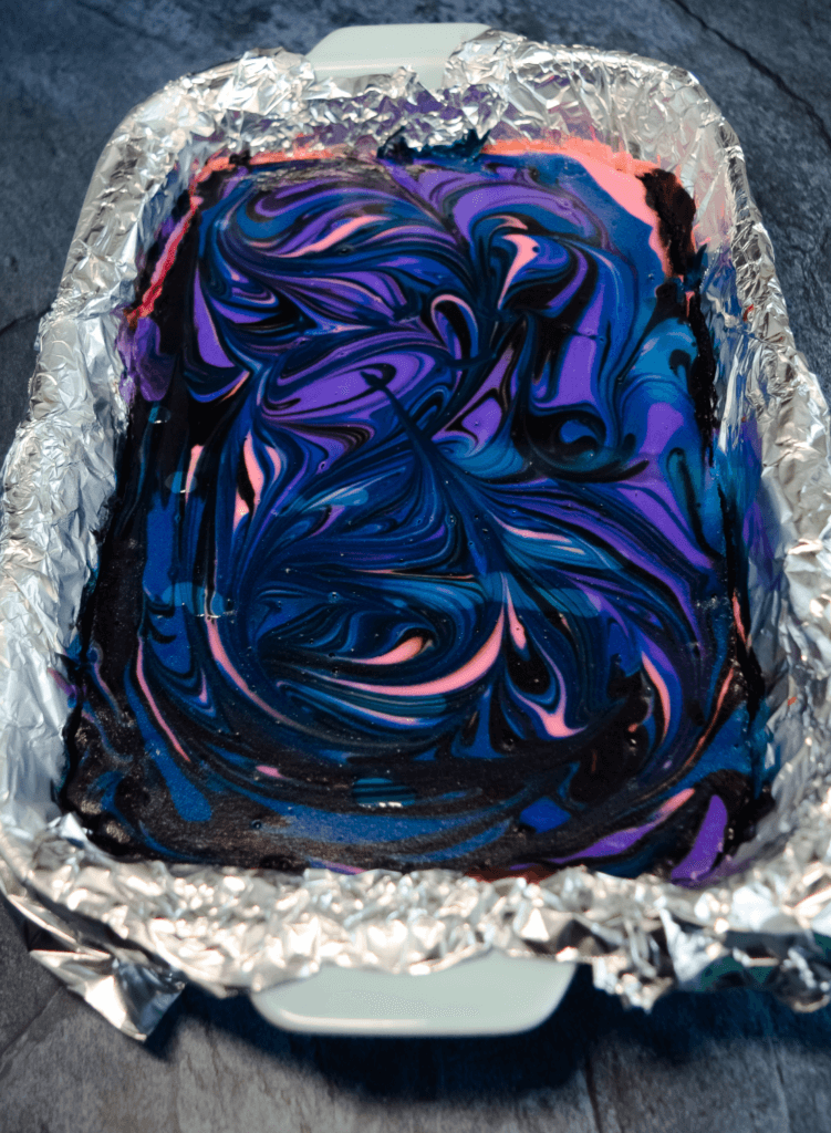 Galaxy cheesecake after baking in swirls of black, blue, pink, and purple. 