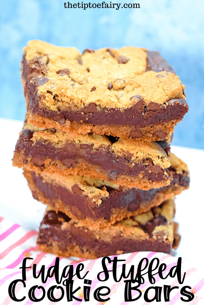 A stack of fudge stuffed cookie bars on a pink striped towel with a blue background. 