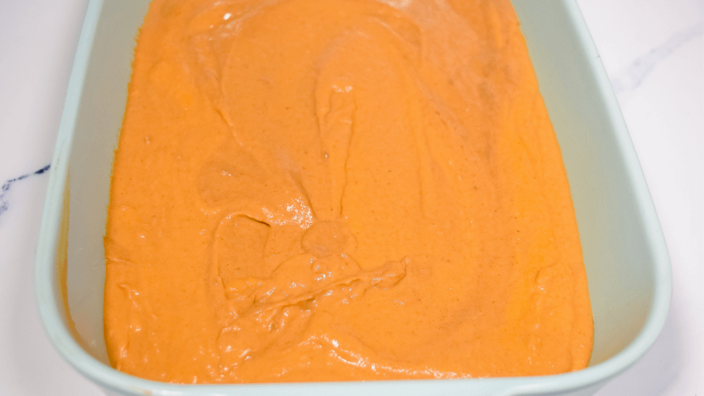 Pumpkin batter in a light blue casserole dish before baking the dulce de leche pumpkin dump cake