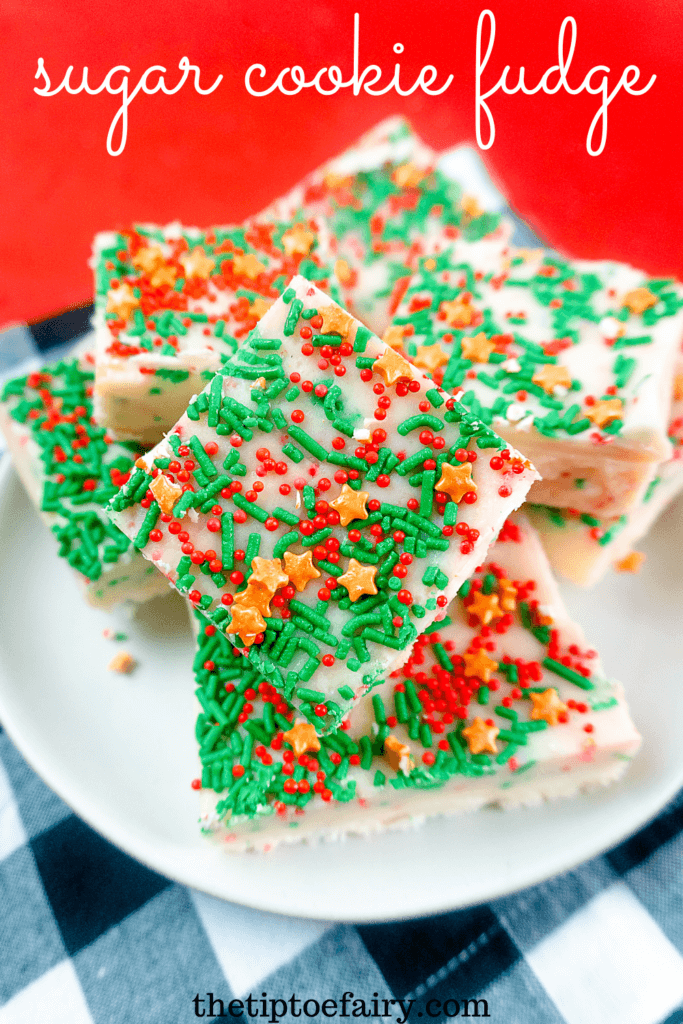 Title image for Sugar Cookie Fudge with close up of squares of fudge full of Christmas sprinkles on a red background. 