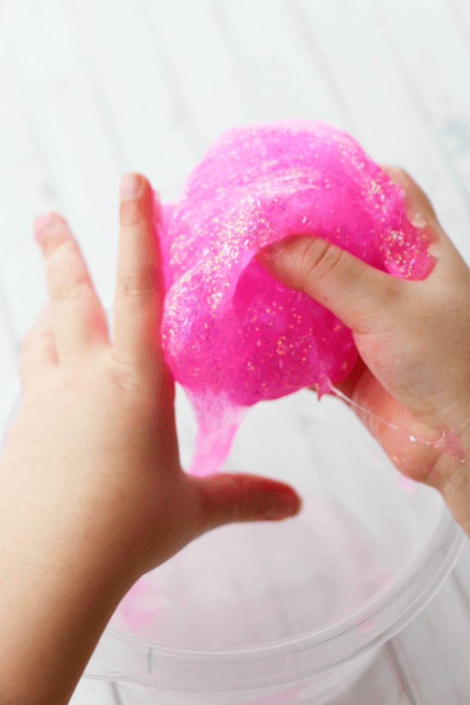 Little hands kneading the pink glitter slime.
