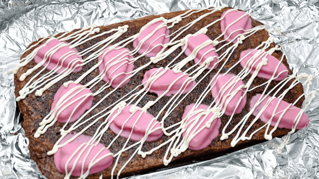 The finished drizzle of the white chocolate chips on the pink heart brownies. 
