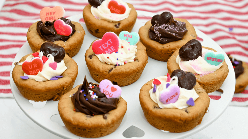 A tiered plate with eight Valentine Cookie Cups all decorated. 