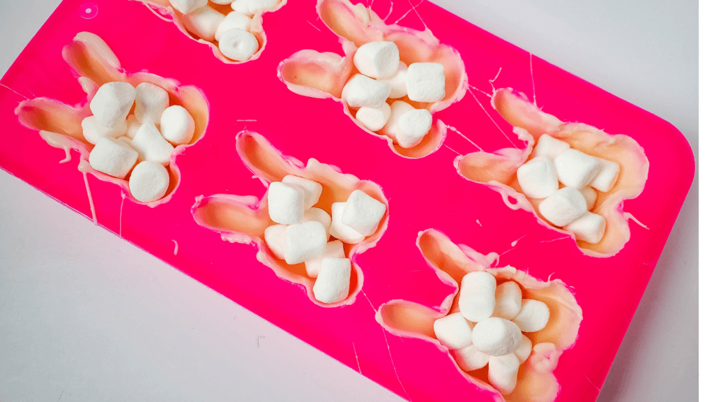 Adding marshmallows to the Easter Bunny Hot Cocoa Bombs.