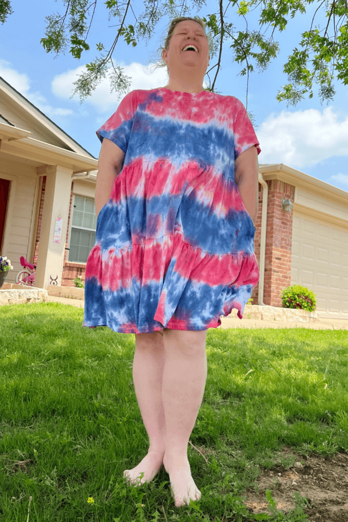 Me modeling my finished red, white, and blue tie dye dress from Old Navy and laughing in front of a house. 