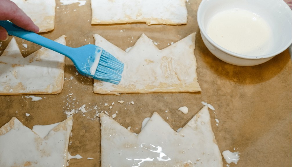 Brushing the puff pastry crowns with a blue basting brush of cream. 
