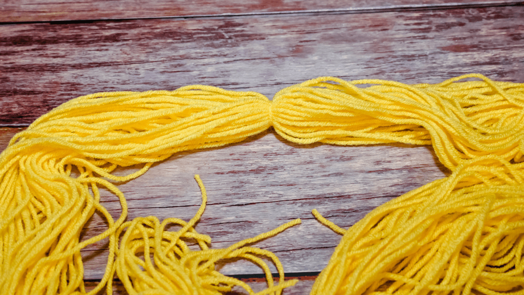 Tying the middle of the yellow yarn.