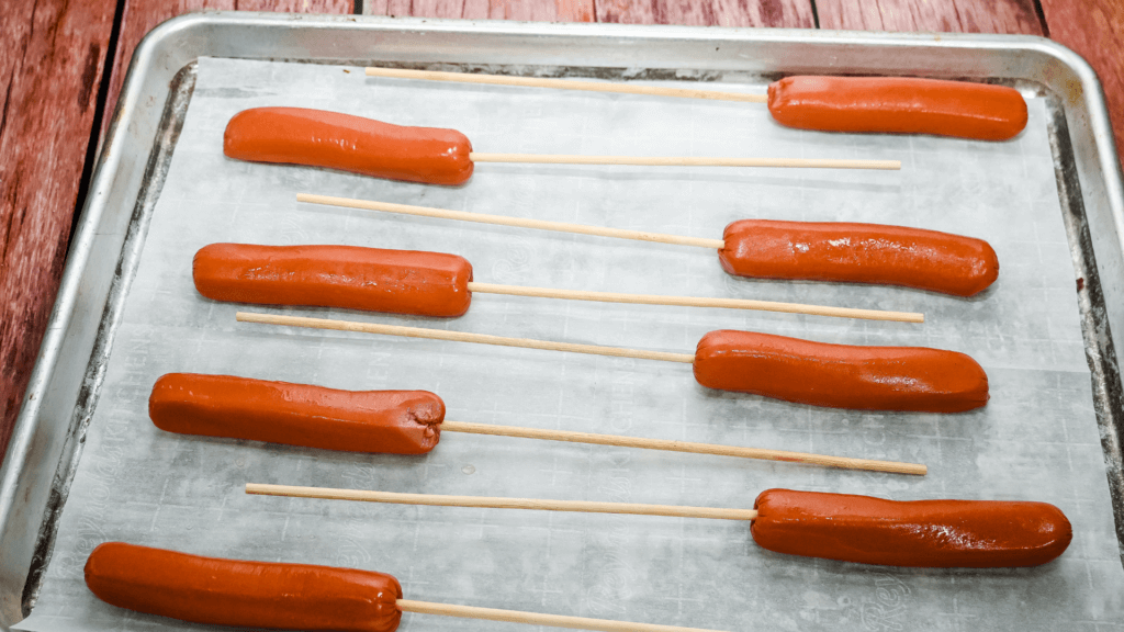 Skewering the hot dogs on a cookie sheet. 
