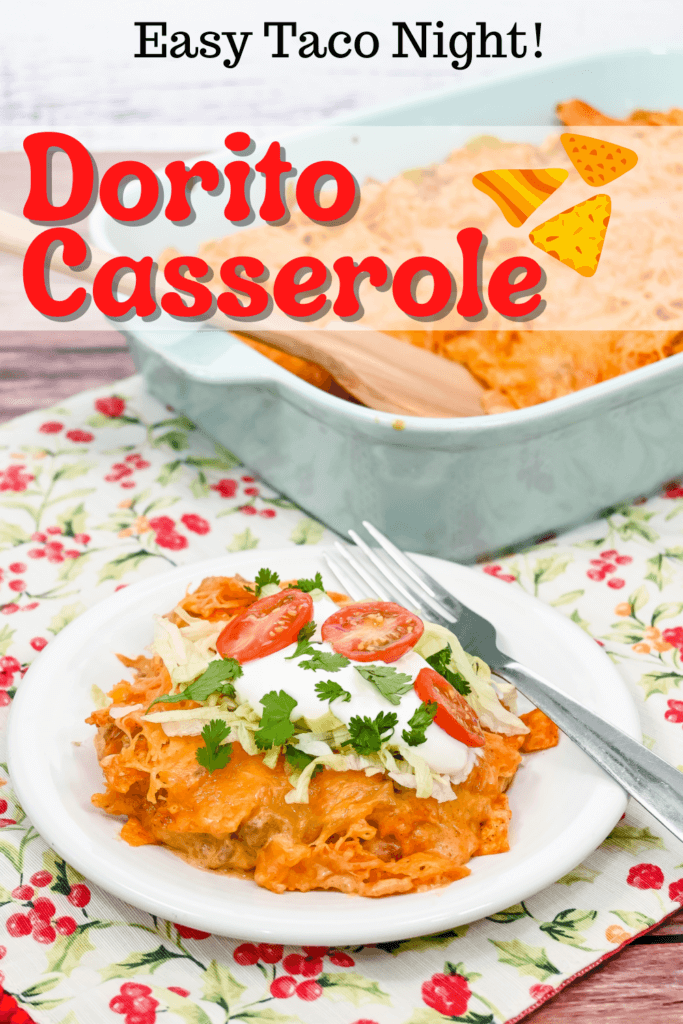 Title image with a white plate filled with Dorito Casserole topped with lettuce, tomatoes, sour cream, and cilantro with a fork on a floral placemat in front of a light blue casserole dish. 